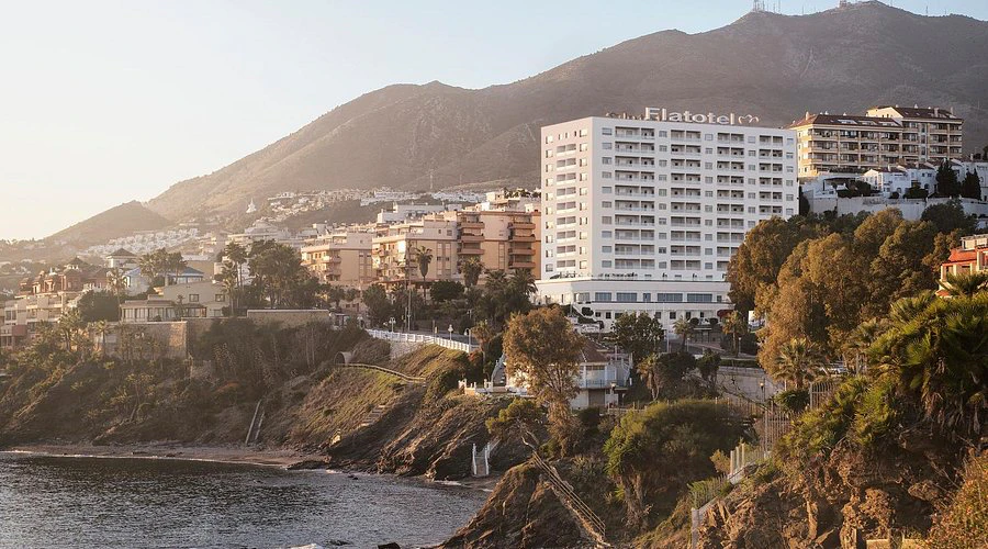 Pobřeží Benalmádeny za podvečerního světla — hotel Flatotel na útesu nad mořem, v pozadí kopce Costa del Sol