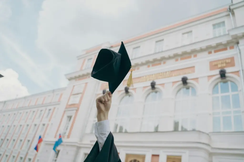 Absolventská čapka zvednutá před budovou školy
