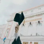 Absolventská čapka zvednutá před budovou školy
