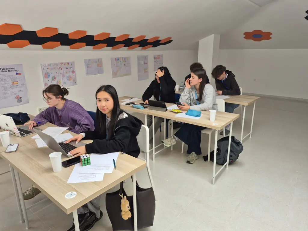 Žáci pracují na projektu ve španělštině u notebooků, na stěnách jejich plakáty o Česku a Španělsku