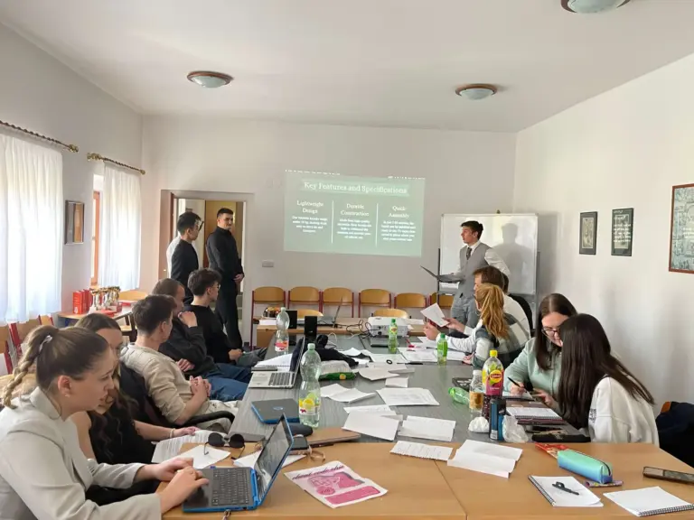 Projektová výuka přímo ve škole — žáci u společného stolu sledují prezentaci lektora